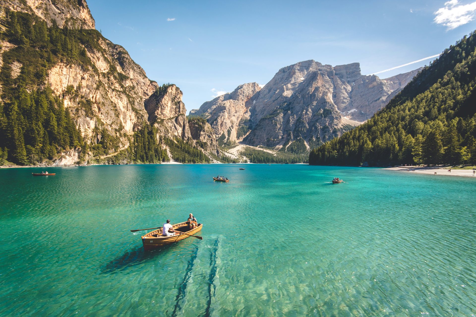Trois bateaux en bois brun sur les eaux bleues d'un lac, photographiés de jour.